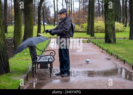 Adult man in jacket and cap puts on gloves in cold rainy weather Stock Photo