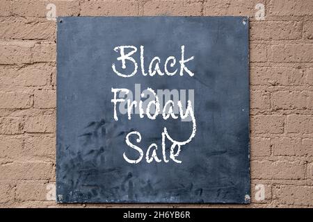 Sign board painted black screwed onto painted concrete block wall -Black Friday Sale written in chalk Stock Photo