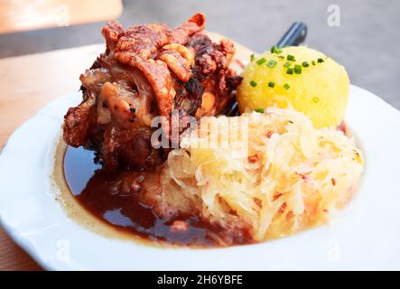 Schweinshaxe, traditional Bavarian cuisine with roasted ham hock (pork knuckle) with cabbage and potato dumpling. Stock Photo