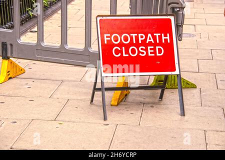 Temporary red Footpath Closed sign outside plastic fencing on London sidewalk - Selective focus Stock Photo