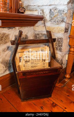 Antique brown stained wooden newspaper bin with old newspapers from 1930s,40s, 50s in dining room inside an old Canadiana circa 1750 fieldstone home Stock Photo