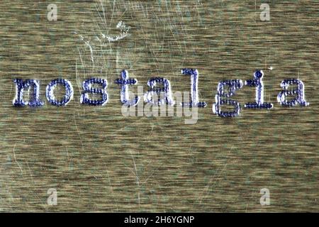 The word "nostalgia" in old manual typewriter font on a scratched and worn surface. Stock Photo