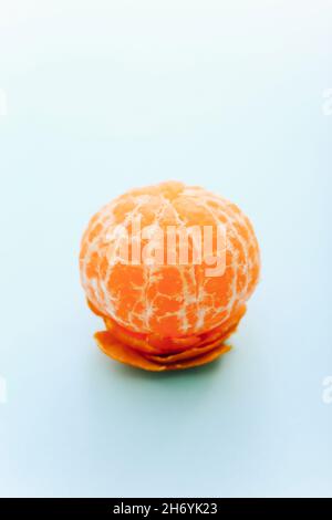 One peeled tangerine on light blue background Stock Photo