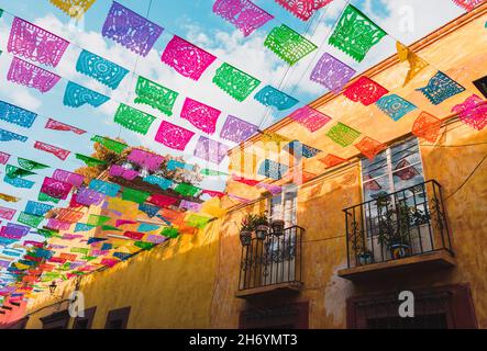 Bright and colorful paper flags over a street in Mexico on a sunny day. Stock Photo