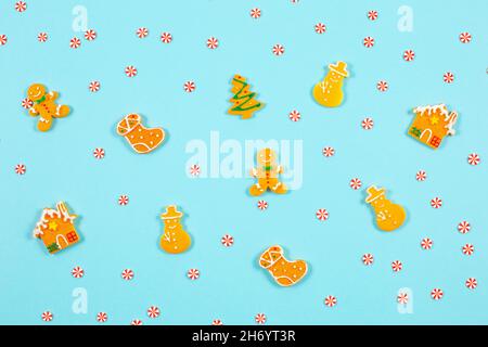 Decorative winter pattern from various gingerbread cookies on blue background. Christmas food pattern. Gingerbread man, snowman, christmas tree, house and mini candies. Flat lay, top view. Flat lay, top view. Stock Photo