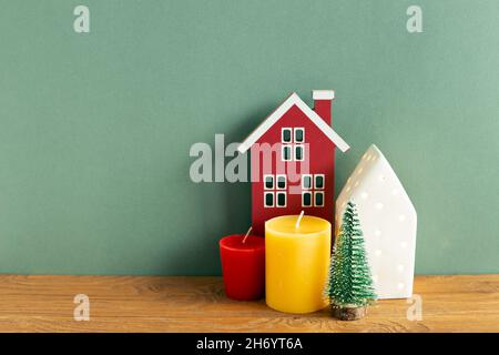 Winter christmas concept. Candle, house model, tree on wooden table. green background. copy space Stock Photo