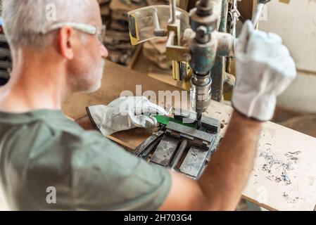 Adult person drilling metal with safety gloves Stock Photo