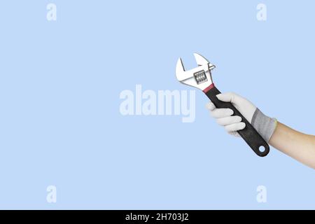 Gloved hands holding spanner construction tools. Work tools on blue background Stock Photo