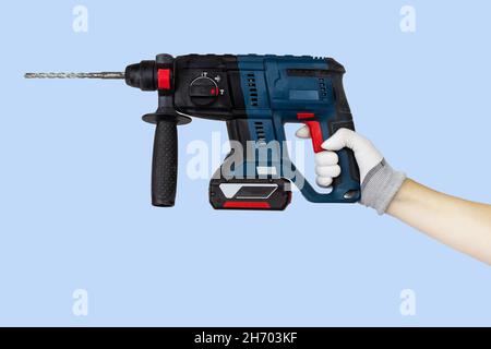 Gloved hands holding drill, perforator construction tools. Work tools on blue background Stock Photo