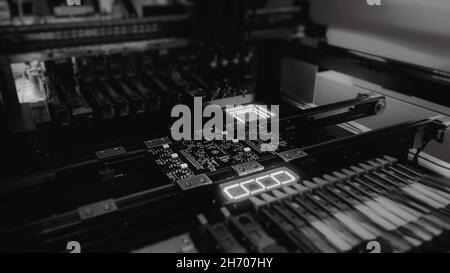 Automatic production of computer chips by SMT Pick and Place machine: black and white shot. Automatic SMT Pick and Place machine picks elements up and places them onto the motherboard.  Stock Photo
