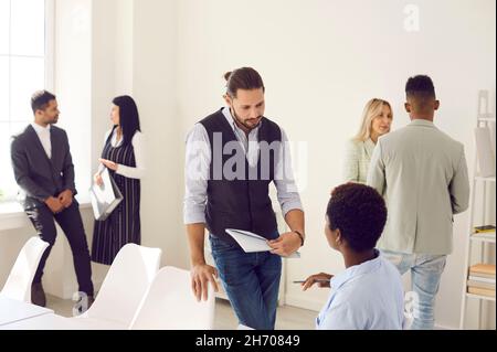 Diverse corporate employees talking in groups while working in company office together Stock Photo