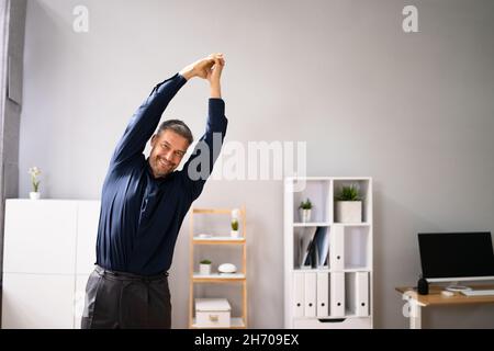 Arms Stretch Exercise Standing Near Desk In Office Stock Photo