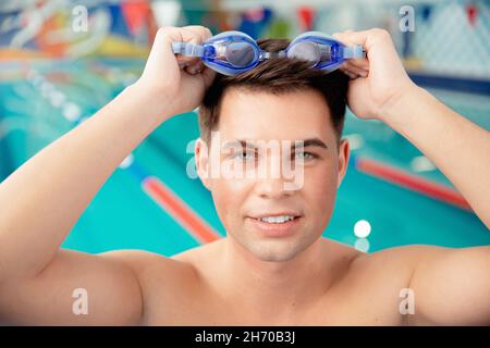Portrait swimmer happy young man, background swimming pool blue water. Stock Photo
