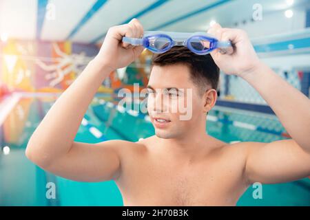 Portrait swimmer happy young man, background swimming pool blue water. Stock Photo