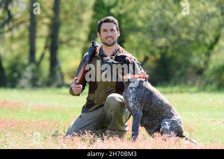 man and his pointer sitting in the woods