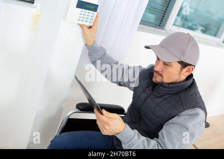 male electrician installing security system door sensor on wall Stock Photo