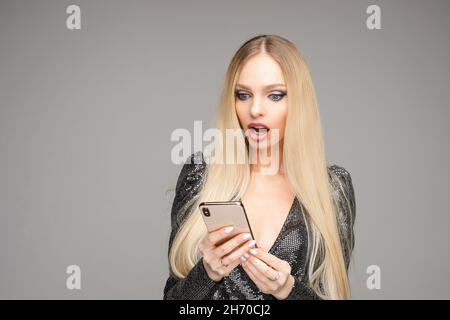 Pretty lady in black dress looking on gadget screen Stock Photo
