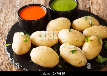 Canarian Wrinkly Potatoes Papas Arrugadas with a mojo rojo and mojo verde sauces close up in the plate on the table. Horizontal Stock Photo