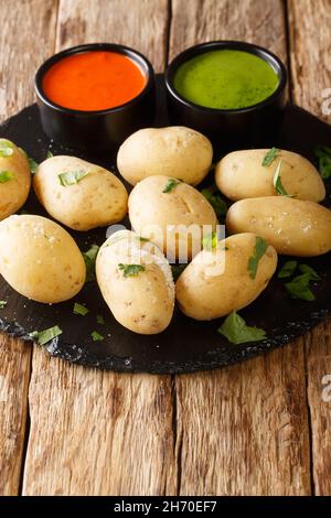 Papas arrugadas wrinkly potatoes is a traditional boiled potato dish served with a mojo rojo and mojo verde sauces close up in the plate on the table. Stock Photo