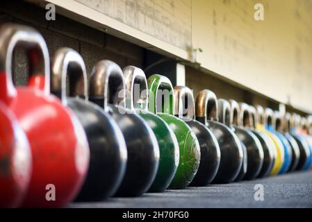 Long row of colorful heavy kettlebells in gym with diminishing perspective. Stock Photo