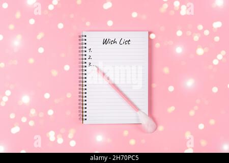 New year, Christmas or holiday wish list concept. Notepad and golden tinsel isolated on pink background. Holiday Banner with copy space Stock Photo