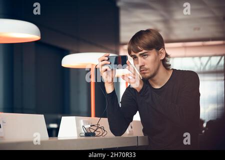Man in library taking photo with cell phone Stock Photo