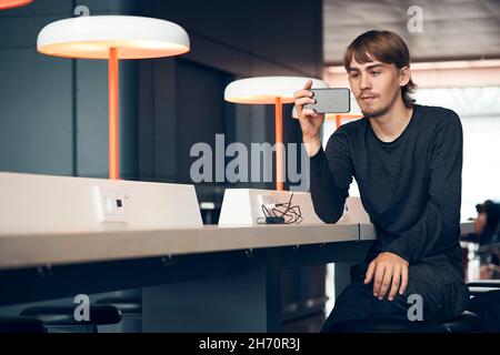 Man in library taking photo with cell phone Stock Photo