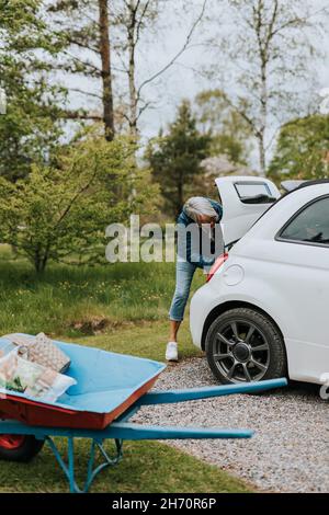 Woman standing in front of open car boot Stock Photo