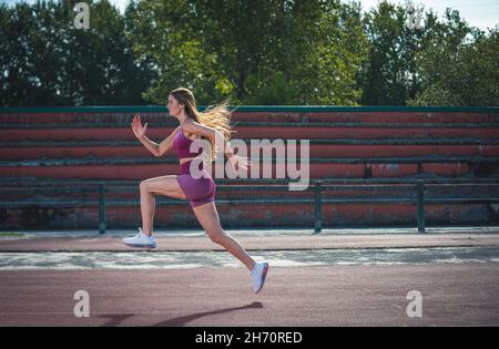 Girl model athlete running on the running track. Stock Photo