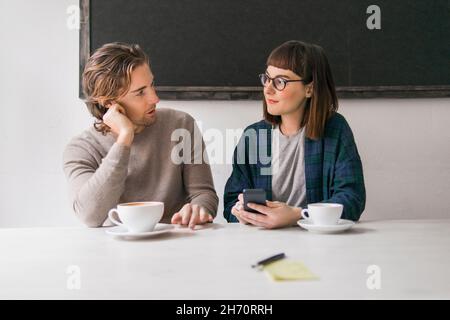 Man and woman using smart phone and drinking coffee Stock Photo