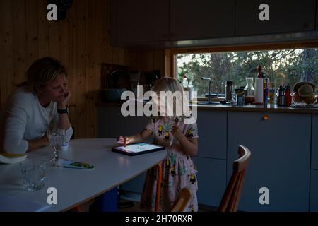 Girl using digital tablet, while mother watching Stock Photo