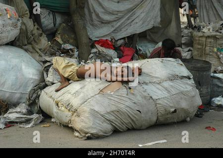 A child sleeps on garbage bags. India. Stock Photo