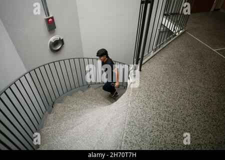 Young woman walking up spiral staircase Stock Photo
