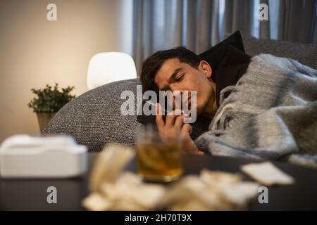 Young man lying on sofa and using smart phone Stock Photo
