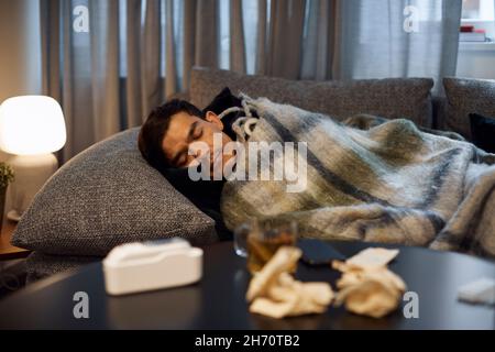 Ill young man sleeping on sofa Stock Photo