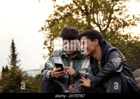 Young men using smart phone outdoors Stock Photo
