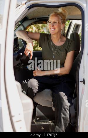 Smiling woman sitting in van Stock Photo