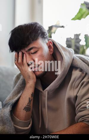 Ill man on sofa with hand covering face Stock Photo