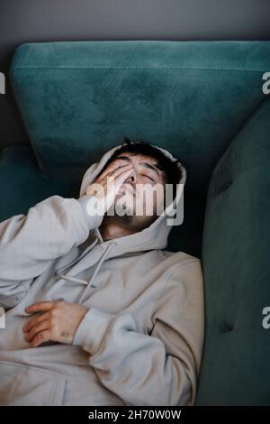 Ill man on sofa with hand covering face Stock Photo