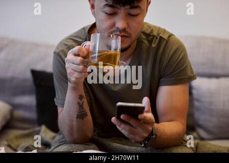 Man on sofa using cell phone Stock Photo