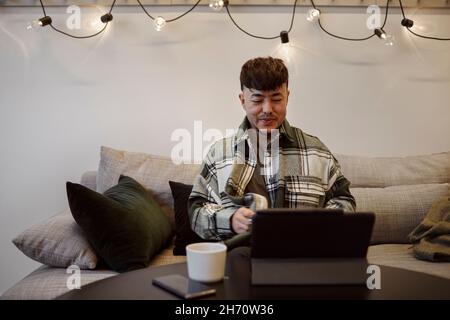 Man on sofa using digital tablet Stock Photo