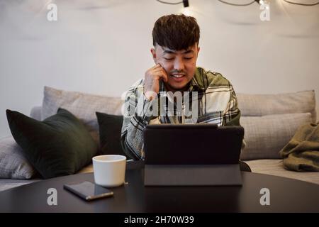 Man on sofa using digital tablet Stock Photo