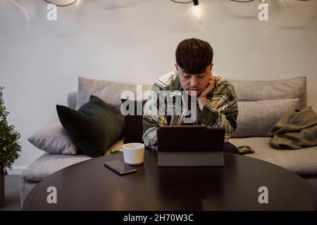 Man on sofa using digital tablet Stock Photo