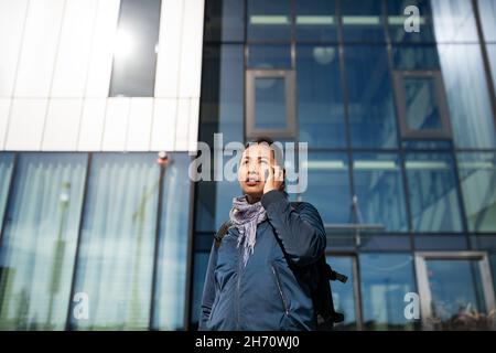 Young woman using phone in front of office building Stock Photo
