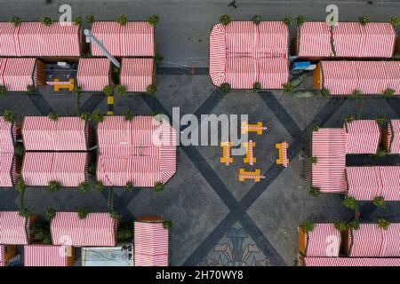 Leipzig, Germany. 18th Nov, 2021. Empty tables stand in empty aisles at a snack bar at the still-closed Leipzig Christmas Market. The market is to take place despite the current Corona situation, but there is to be no serving of alcohol. The mulled wine ban is intended to prevent uncontrolled, hour-long gatherings of people. (Aerial view with a drone) Credit: Jan Woitas/dpa-Zentralbild/ZB/dpa/Alamy Live News Stock Photo