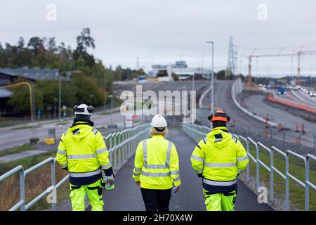 Construction workers walking along road Stock Photo