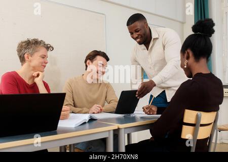 Teacher helping students in classroom Stock Photo