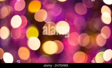 Yellow and purple glitter and abstract festive elegant background with blurred bokeh lights. Defocused holiday lighting. Stock Photo