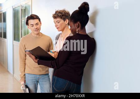 Teacher and students talking at corridor Stock Photo