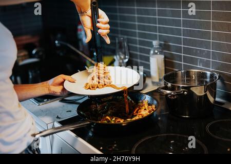 Woman putting spaghetti on plate Stock Photo